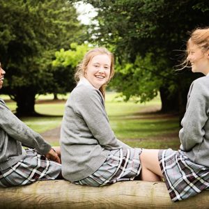 3 girls sat on a log