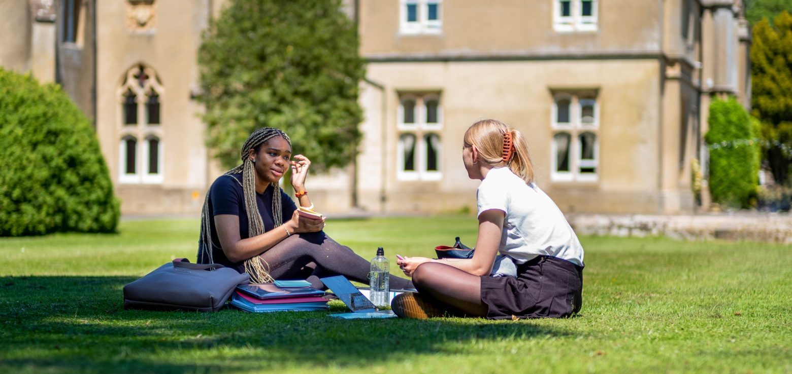 girls sat on the grass together