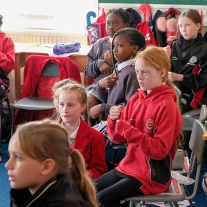 children sitting on chairs in the middle of a classroom