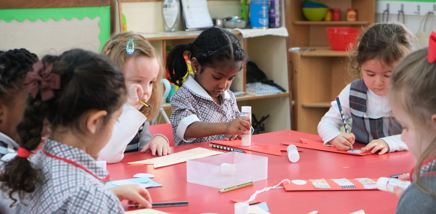 reception students cutting and sticking