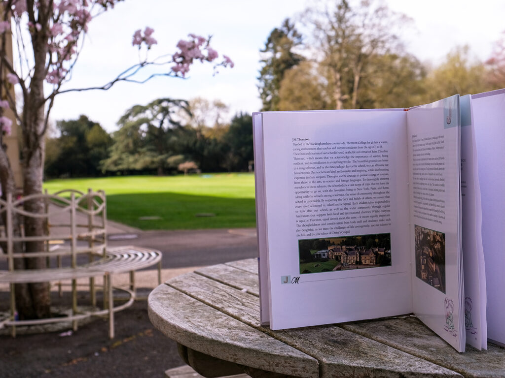 A book propped open on a wooden outdoor table