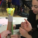 children attaching a ball to tissue rolls
